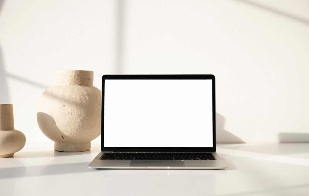 A blank white screen on a computer with a warning sign, symbolizing the WordPress White Screen of Death (WSOD) caused by plugin conflicts.